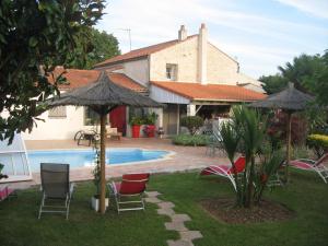 a house with a swimming pool with chairs and umbrellas at La Roseraie in Trizay