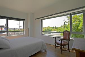 a bedroom with a bed and a chair and windows at TOLETUM low cost LOFTS dúplex diáfanos o 2dormitorios PARKING Municipal Gratis al aire libre a 100m in Toledo