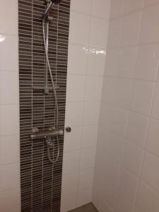 a shower in a bathroom with white tiles at Apartment Asemakatu 20 in Kuopio
