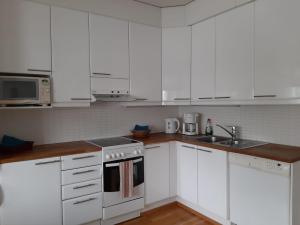 a white kitchen with white cabinets and a sink at Apartment Asemakatu 20 in Kuopio +4 photos