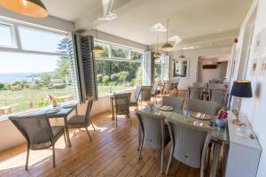 a dining room with tables and chairs and a large window at The Rosevine in Porthscatho