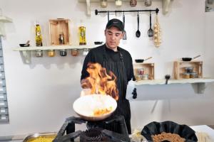 a man cooking food in a pan on a grill at Acrotel Elea Beach in Elia