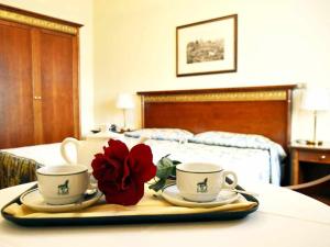 a tray with two cups and a red flower on a bed at Hotel Donatello in Padova