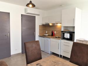 レ・ゼペスにあるHameau Colbert - 3km du PuyduFouの白いキャビネット、テーブルと椅子付きのキッチンが備わります。