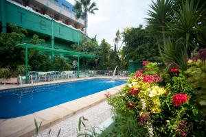 a swimming pool with flowers next to a building at Hotel Europa in Alfaz del Pi