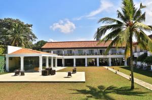 a building with a palm tree in front of it at Hibiscus Beach Hotel & Villas in Kalutara