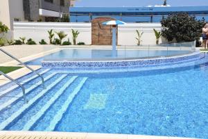 ein großer blauer Pool mit Sonnenschirm in der Unterkunft Kapparis Apartment Mythical Sands in Protaras