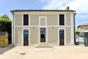 a white house with black shuttered windows at La Casa al Mare in Civitanova Marche
