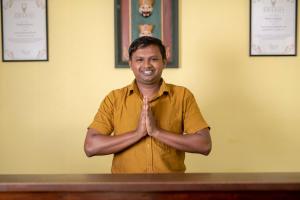 Een man in een geel shirt doet een gebaar. bij Melheim Kandy Villas in Kandy