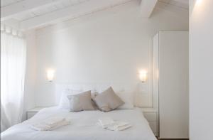 um quarto branco com uma cama branca com 2 toalhas em Sweet Corner em Castelnuovo del Garda