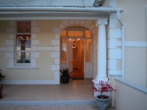 a front porch of a house with an arch and flowers at Cheviot Place Guest House in Cape Town +15 photos