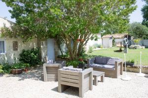 a patio with couches and chairs under a tree at Le Charhido in Saint-Fort-sur-Gironde