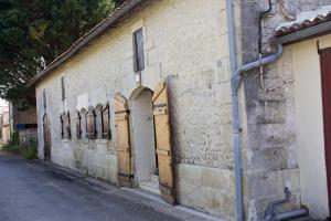 an old brick building with wooden doors on it at Le Charhido in Saint-Fort-sur-Gironde