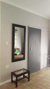 a room with a mirror and a bench in front of a door at Caesar's Self-catering Open Plan Suite in Somerset West