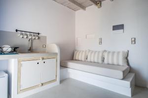 a white kitchen with a bench and a sink at Κymanemi Folegandros in Agali