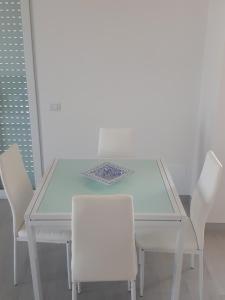 a white dining table with white chairs in a room at casanelmare in Mola di Bari