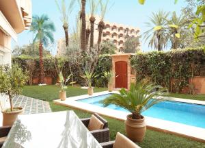 a backyard with a swimming pool and palm trees at The Ruby Apartment with Private Swimming Pool - Hivernage Quarter - By Goldex Marrakech in Marrakesh