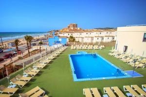 a swimming pool with lounge chairs and the beach at Hotel Servigroup Koral Beach in Oropesa del Mar