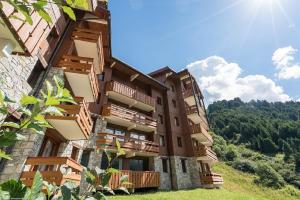 a building with wooden balconies on a hill at Residence Les Sentiers du Tueda - maeva Home in Méribel