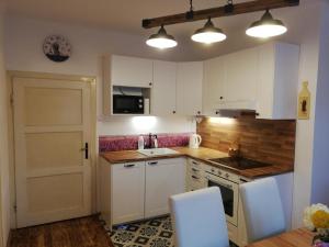 eine kleine Küche mit weißen Schränken und einer Tür in der Unterkunft Villa Oliva in Český Krumlov