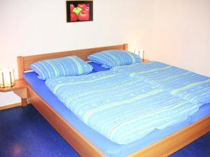 a bed with a blue comforter and two pillows at holiday home Kellerwald Edersee National Park in Bad Wildungen