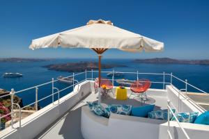 a balcony with an umbrella and chairs on a boat at Barocco Bello Villa in Fira