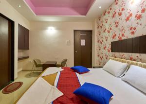 a bedroom with a bed with blue pillows and a table at Hotel Ganeshratna Executive in Kolhapur