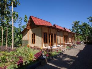 a small house with a red roof in a garden at RedDoorz near Banyuwangi Kota Train Station in Banyuwangi
