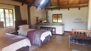 a room with two beds and a kitchen in it at African Flair Country Lodge in Piet Retief