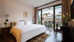 a bedroom with a white bed and a large window at Centraltique Downtown - Bespoke Colonial House Near Hoan Kiem Lake in Hanoi