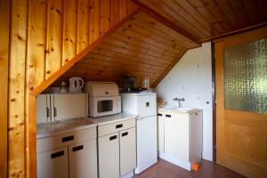 a kitchen with white appliances and a wooden ceiling at Szabó Vendégház in Siklós