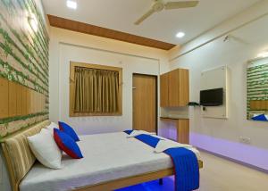 a bedroom with a bed with blue pillows at Hotel Ganeshratna Executive in Kolhapur
