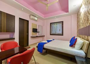 a bedroom with a bed and a desk and chairs at Hotel Ganeshratna Executive in Kolhapur