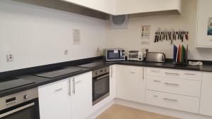 a kitchen with white cabinets and black counter tops at Port Charlotte Youth Hostel in Port Charlotte