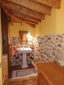 Un baño con lavabo y pared de piedra. en Apartamentos Rurales A Torre, en Santa María