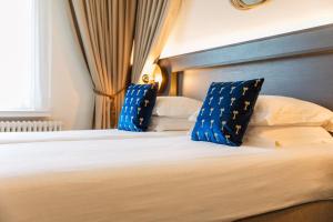 een slaapkamer met een bed met blauwe en witte kussens bij C-Hotels Continental in De Panne