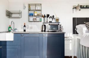 a kitchen with blue cabinets and a microwave at Purbeck Shepherd Huts in Worth Matravers