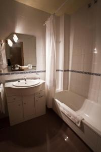 een badkamer met een wastafel, een bad en een douche bij Hotel Bello in O Pino 
