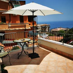 d'une terrasse avec une table et un parasol sur le balcon. dans l'établissement Apartment Marifra Garden, à Taormine