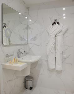 a white bathroom with a sink and a mirror at Belvedere Nevsky Business Hotel in Saint Petersburg