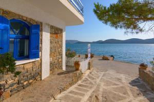 a house with a blue window next to the water at Eleftheria Sea Side Traditional House in Elounda