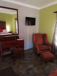 a room with a chair and a mirror and a piano at Makarios Lodge in Polokwane