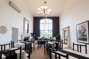 une salle à manger avec des tables et des chaises ainsi qu'un lustre dans l'établissement The Lodge at Atlantic Beach, à Melkbosstrand