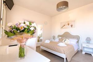 una camera da letto con un letto e un vaso di fiori su un tavolo di Agriturismo Il Megalite a Giurdignano