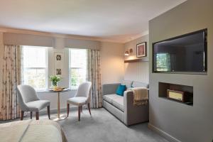 un salon avec un canapé et une table avec des chaises dans l'établissement Burnham Beeches Hotel & Spa, à Slough