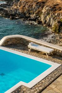 een zwembad met een bank naast het water bij Villa Coventina, Ornos - Cavo Delos, Mykonos in Agios Ioannis Mykonos