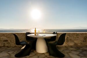 een tafel en stoelen met een tafel en de oceaan bij Villa Coventina, Ornos - Cavo Delos, Mykonos in Agios Ioannis Mykonos