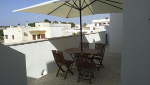 a table and chairs with an umbrella on a balcony at Casa Vacanze Leo 2 in Acquarica del Capo