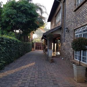 a brick walkway next to a building with a tree at Falling Feather Inn in Pretoria