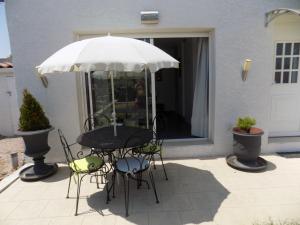a table and chairs under an umbrella on a patio at Villa VAYA in Villemoustaussou
